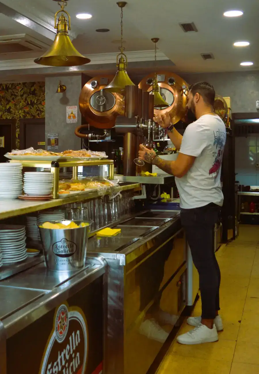 Camarero sirviendo cerveza de grifo en la barra de Café Bar Plaza en Palencia